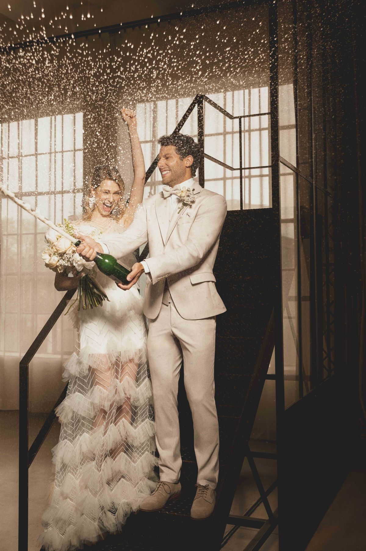 Hochzeitspaar knallt eine Champagnerflasche im Haus, feierliche Stimmung, elegante Hochzeitskleidung.